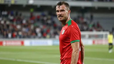 Mid-30s muscular forward, sweat-glazed skin, head turned toward camera, eyes fierce, celebrating a goal for Fredrikstad FK;