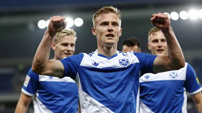 A tight action crop of an anonymous Fredrikstad FK player celebrating the decisive goal with his teammates, wearing blue...